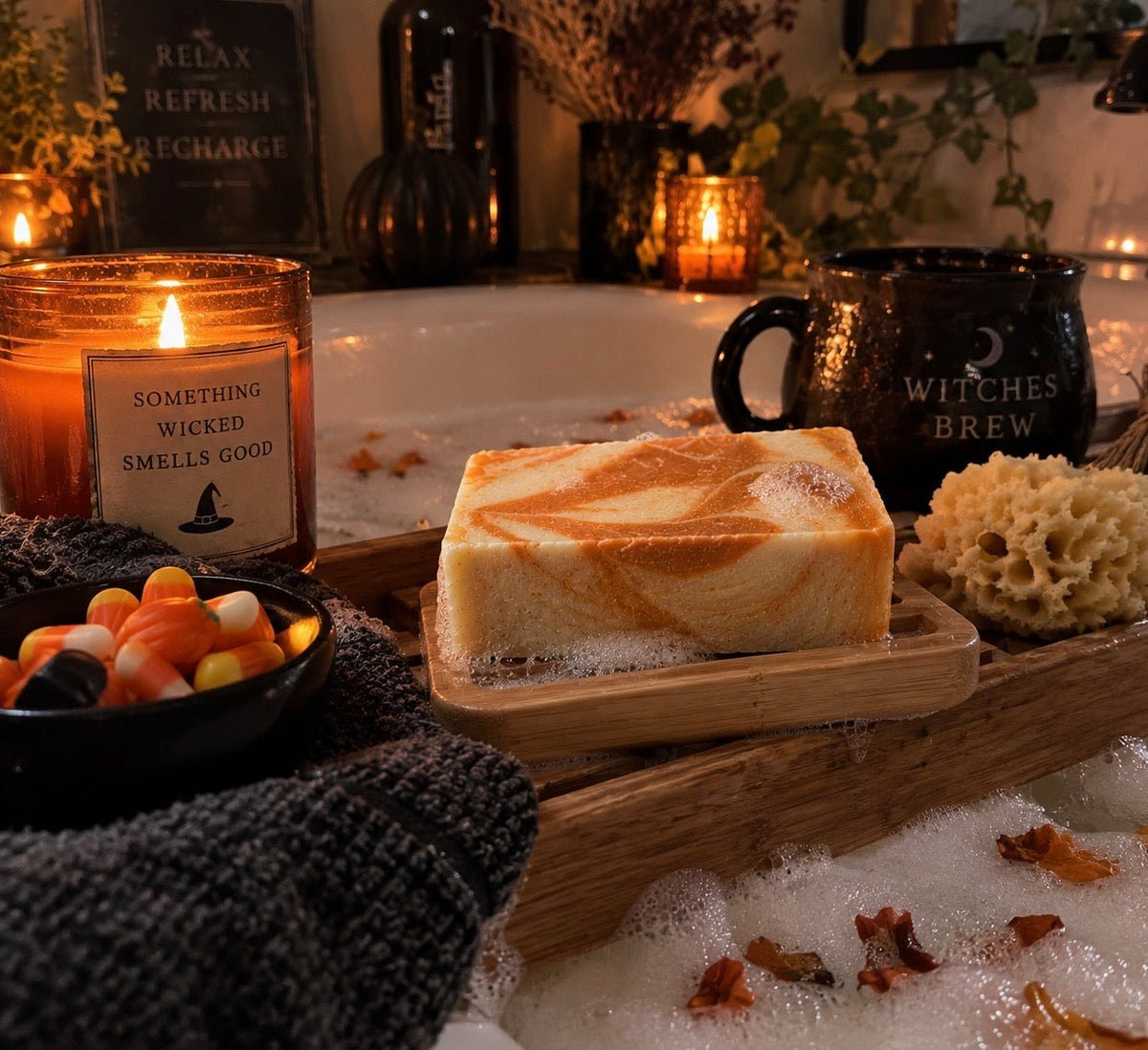 Bare Daily limited edition Candy Cauldron goat milk soap next to a bubble bath and festive Halloween props