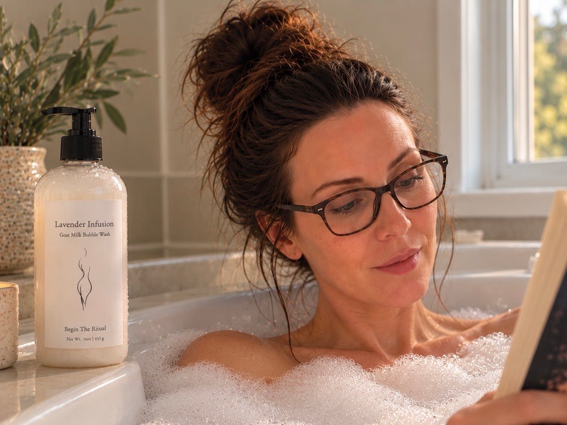 Woman relaxes in bubble bath reading a book with Bare Daily Goat Milk Lavender Infusion Bubble Bath sitting in a clear bottle with black pump resting at the edge of bathtub. 