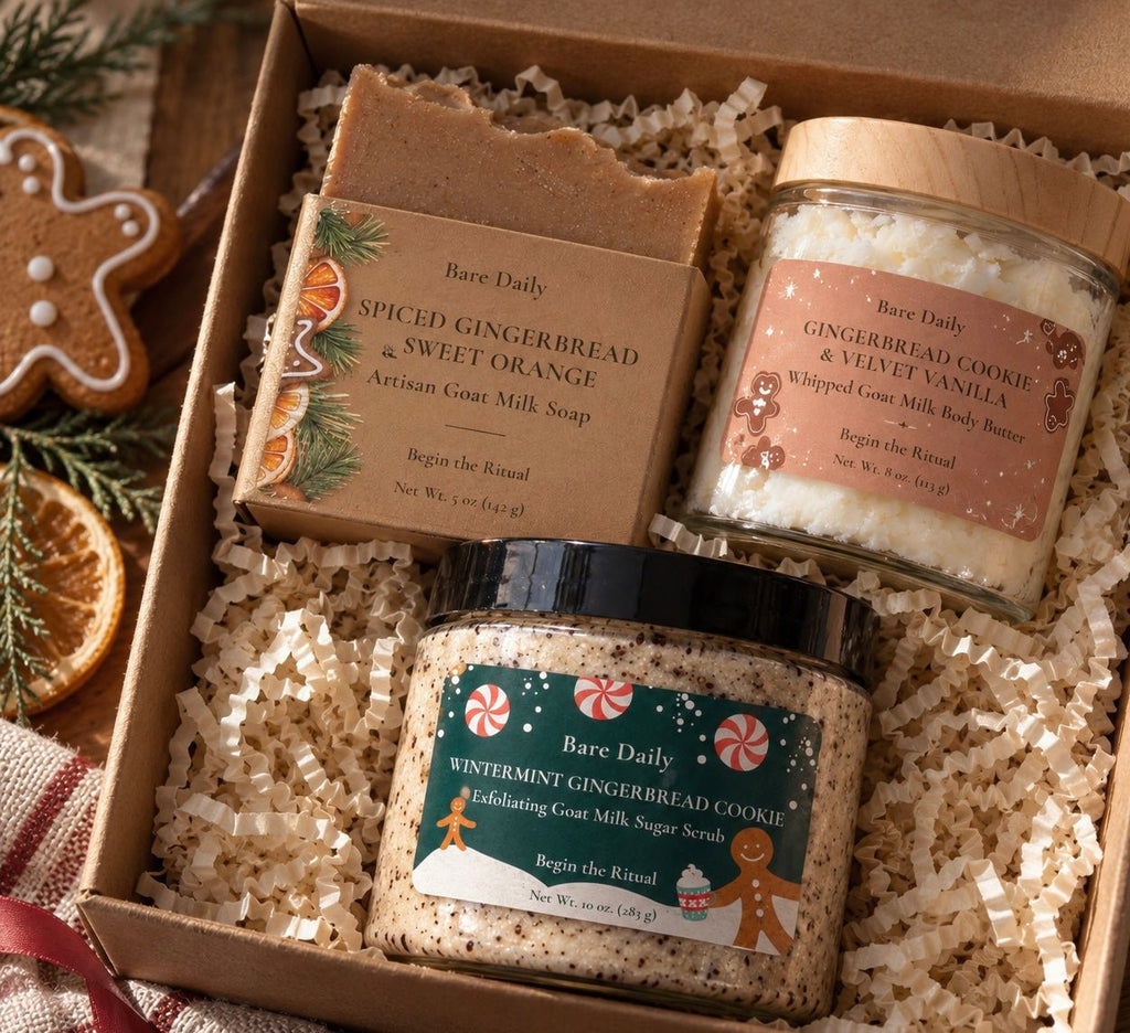 A Bare Daily gift set in a cardboard box filled with white crinkle paper, featuring three products: a bar of Spiced Gingerbread & Sweet Orange artisan goat milk soap, a jar of GINGERBREAD COOKIE & VELVET VANILLA whipped goat milk body butter, and a jar of WINTERMINT GINGERBREAD COOKIE infusing goat milk sugar scrub.