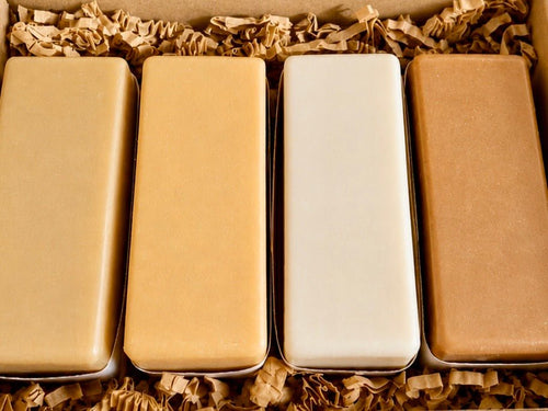 Four rectangular boxes in different colors arranged in a row on crinkled brown paper.