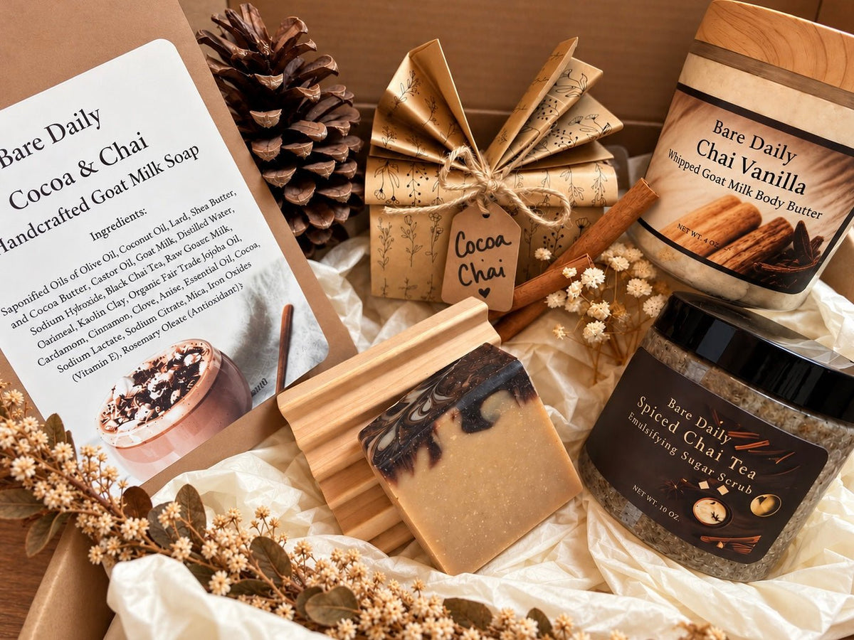 A curated seasonal fall gift set in a wooden box featuring Bare Daily handcrafted soap and body butter products, including Cocoa & Chai and Chai Vanilla, along with a wrapped gift box, a pinecone, cinnamon sticks, dried flowers, and a soap dish.